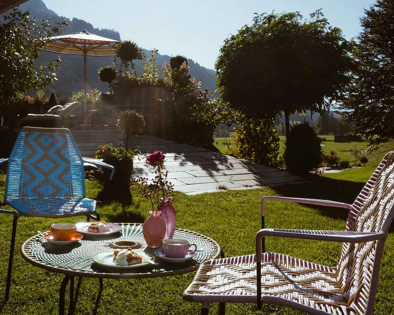 Bunte gedeckter Gartentisch mit Kuchen und Kaffee in der Sonne